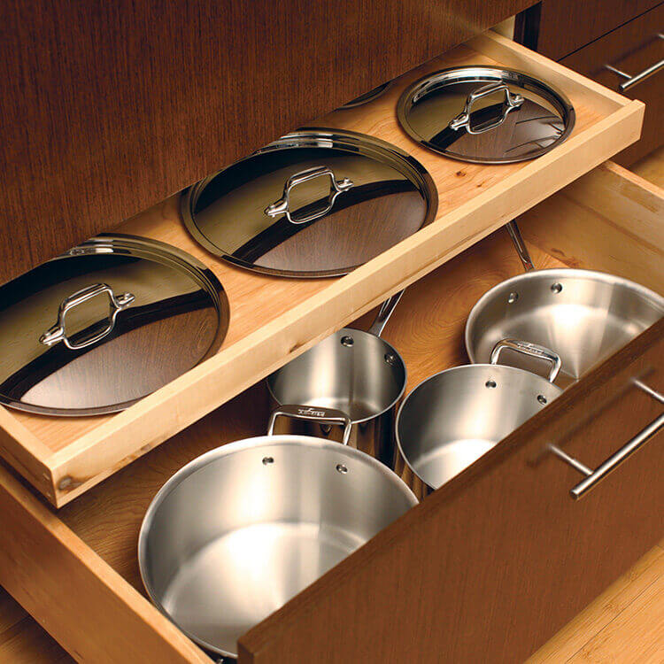 A shallow roll-out above a drawer works great for lid storage for pots and pans! This modern kitchen design has organized kitchen storage in deep cabinet drawers.