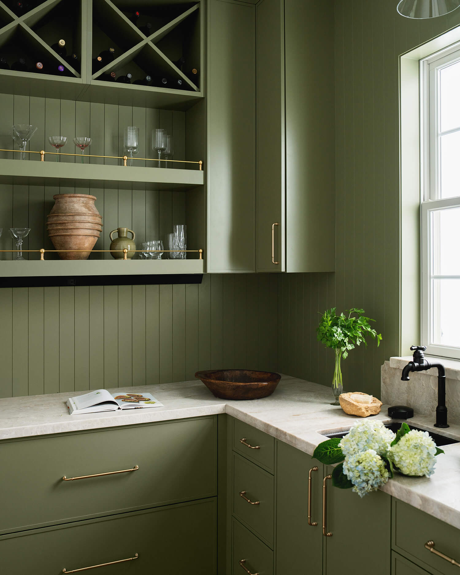 A butler's pantry color drenched with Olive Green painted cabinets featuring beautiful voided corner storage.