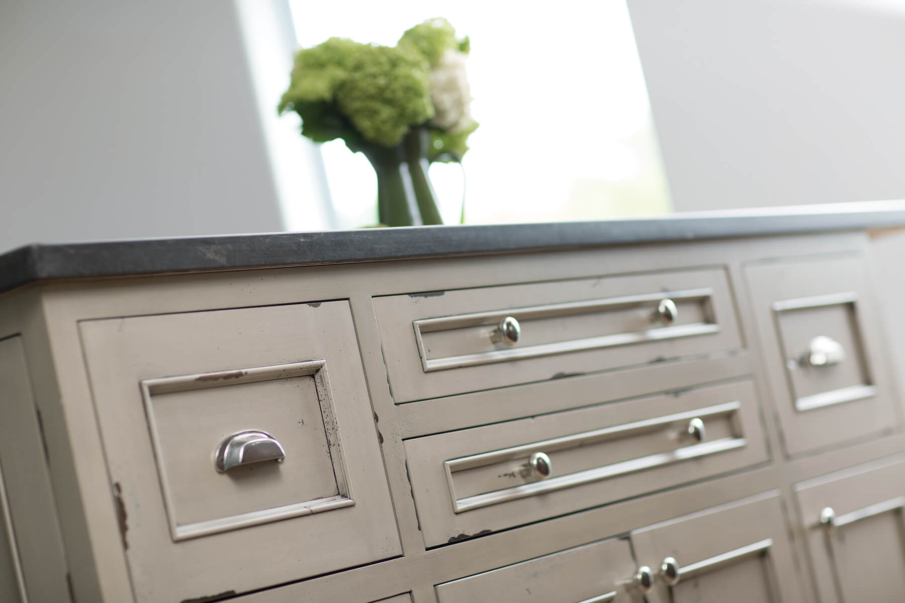 A shabby chic and traditional styled kitchen island showing 5-peice drawer fronts in several different sizes next to each other.