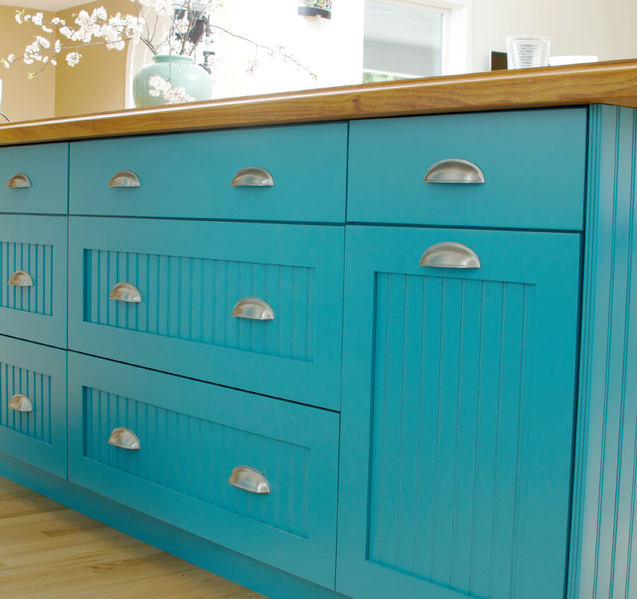 Bright aqua blue cabinets with cottage style cabinet doors on a long kitchen island.