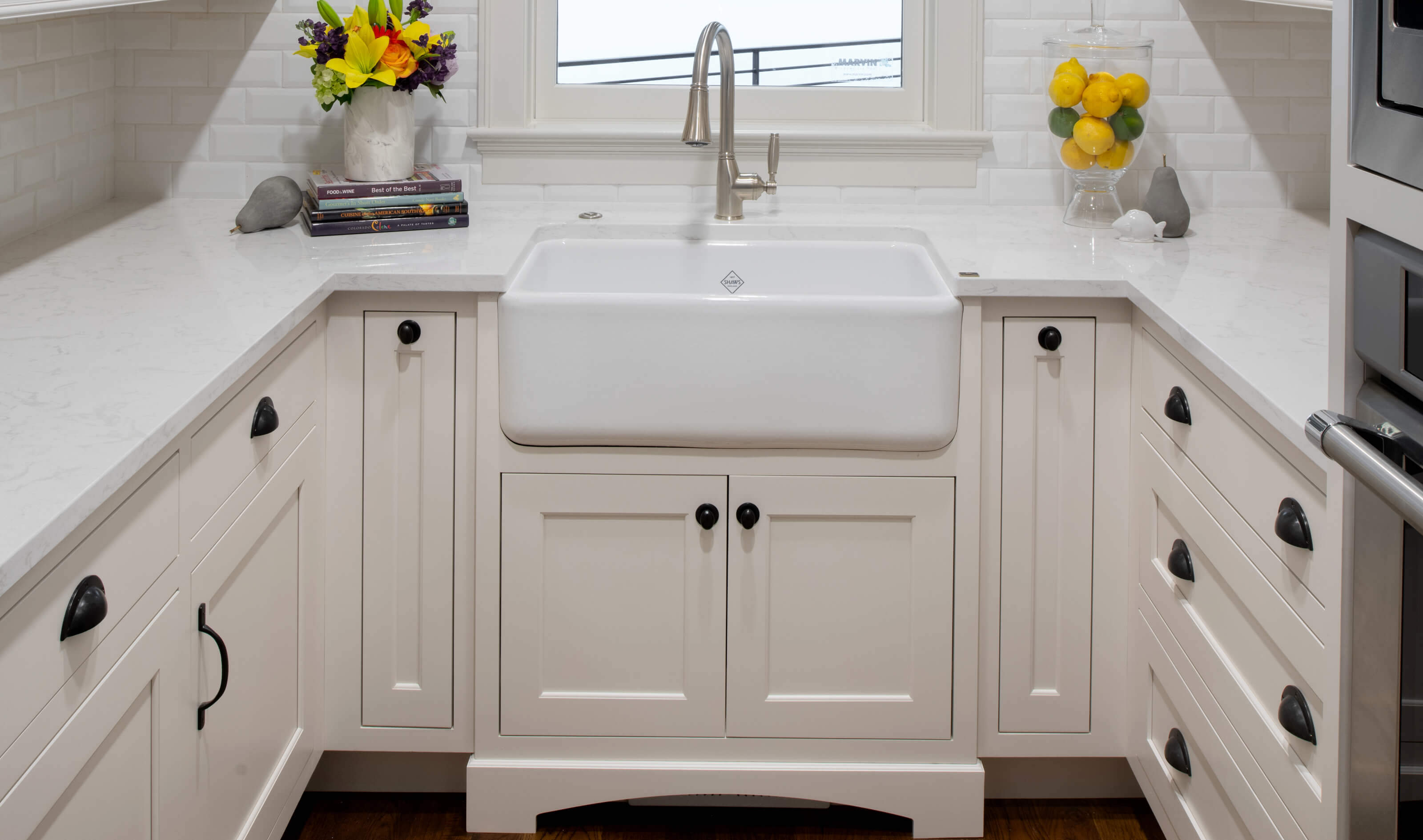 A sink base cabinet with a bump-out and decorative toe kick detail with white inset cabinets from Dura Supreme.