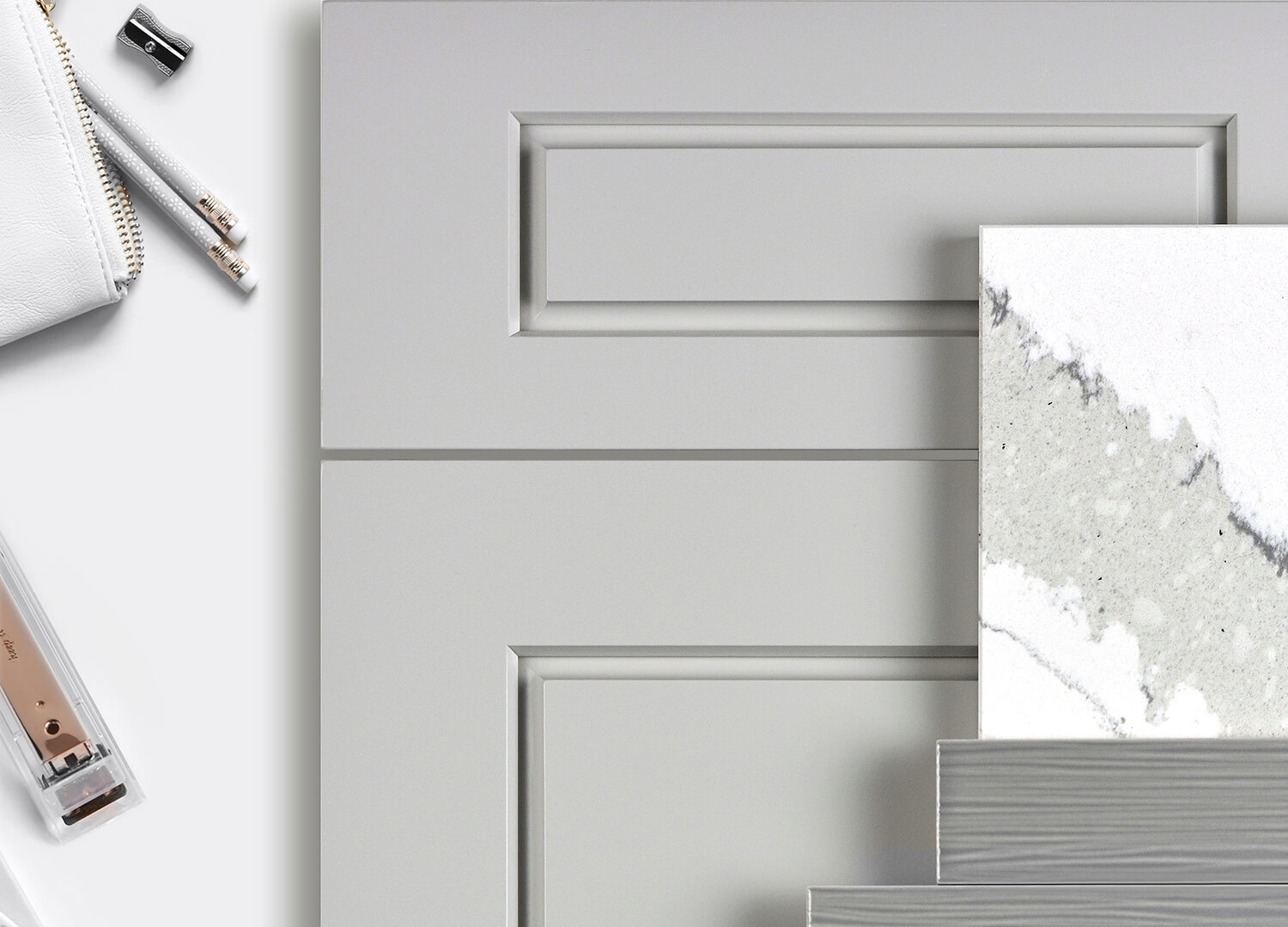 A flat lay showing a kitchen design mood board with an all gray color palette using a modern raised panel door with a gray painted finish as well as gray and white tiles and countertop samples.