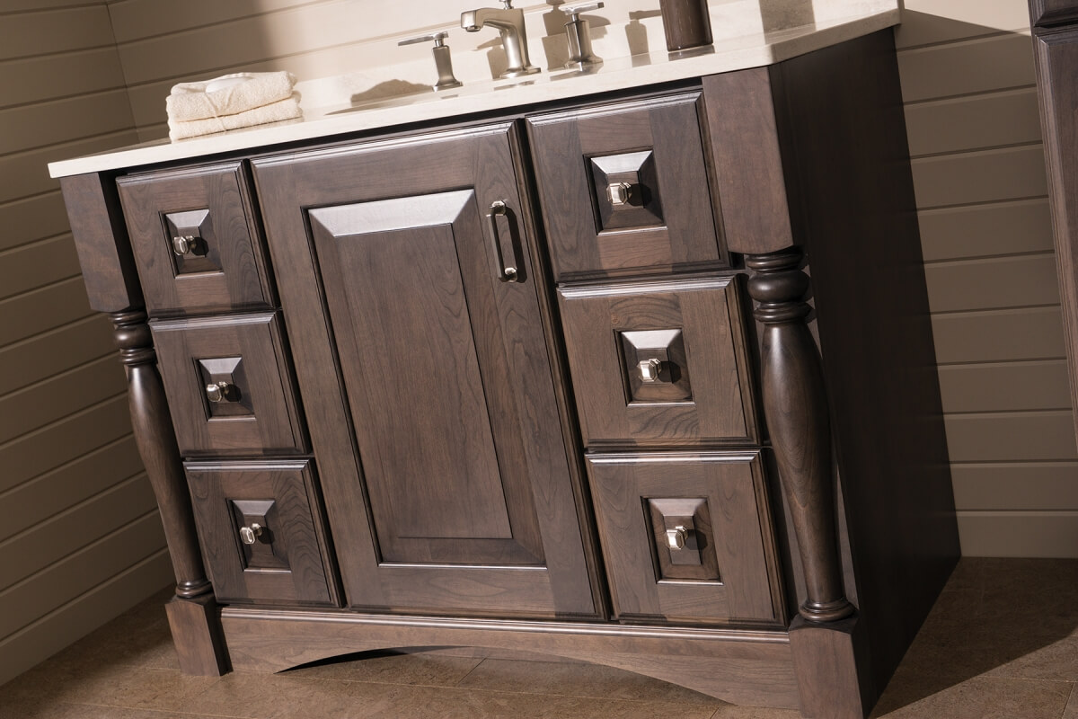 A dark stained bathroom vanity with a furniture style.