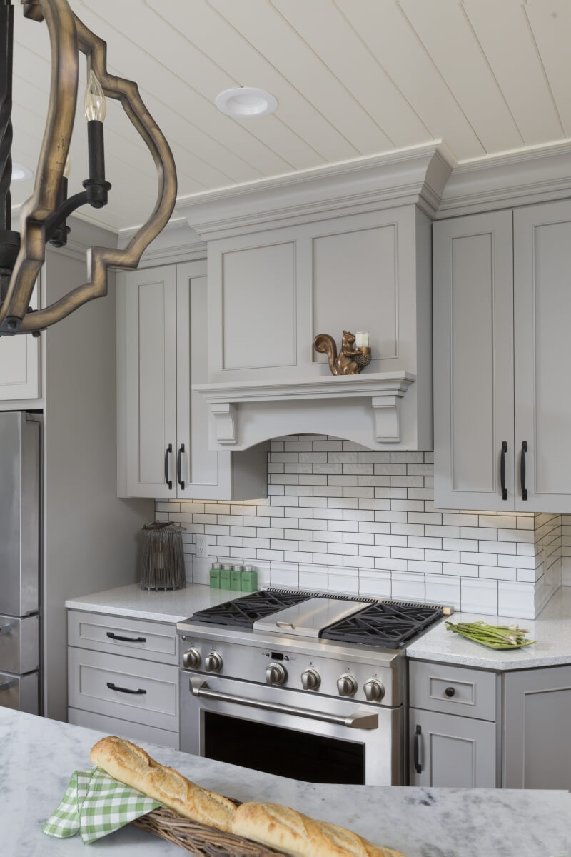 A pray painted traditional kitchen remodel with a mantel wood hood from Dura Supreme Cabinetry.