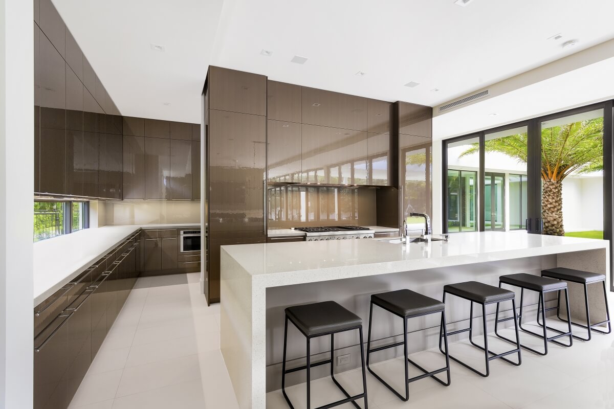 Dura Supreme kitchen design by Danny McMullen of Distinguished Kitchens and Baths. An ultra modern style kitchen with glossy cabinets and a waterfall countertop.