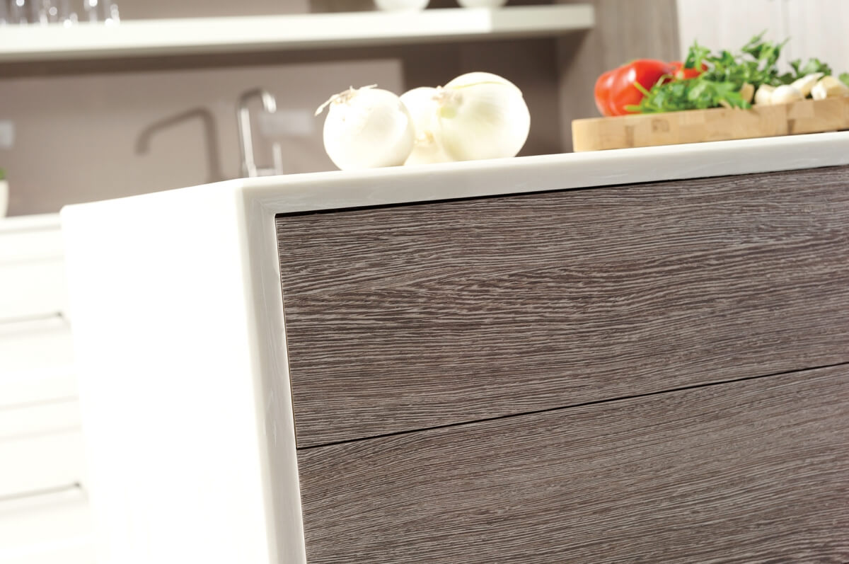 A close up of a contemporary kitchen island with a thin, white waterfall countertop and textured shiplap panels.