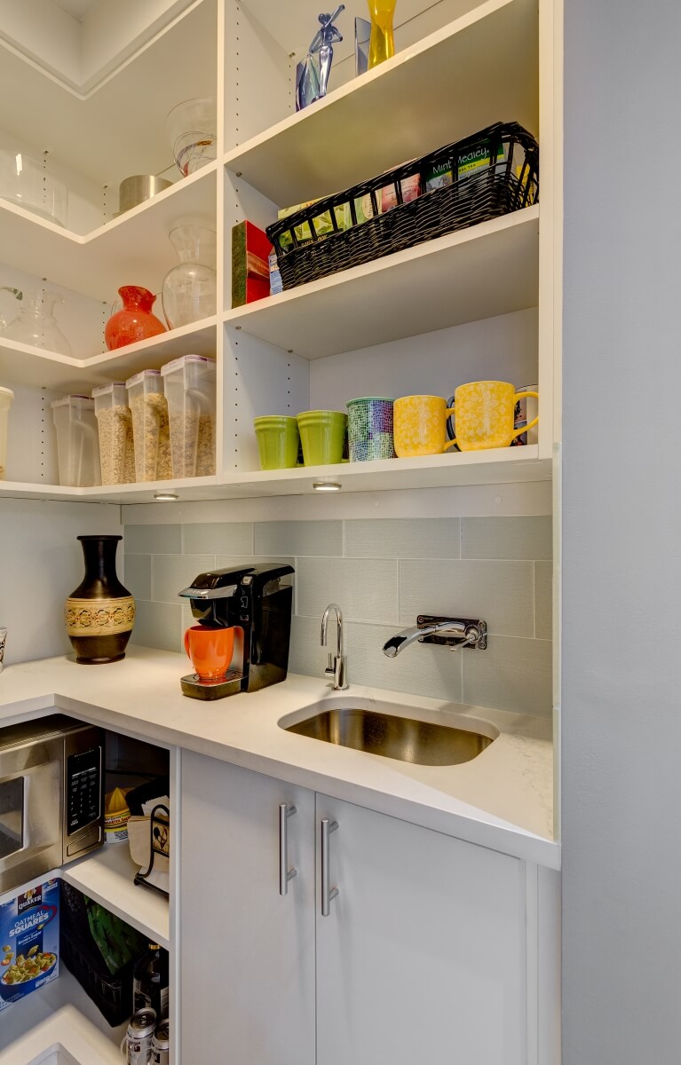 View inside pantry with microwave, sink, and lots of open shelf storage.