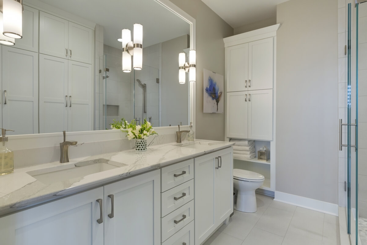 A Transitional style bathroom featuring white undermount sinks and Dura Supreme Cabinetry. Designed by Ispiri Design Build Remodel.