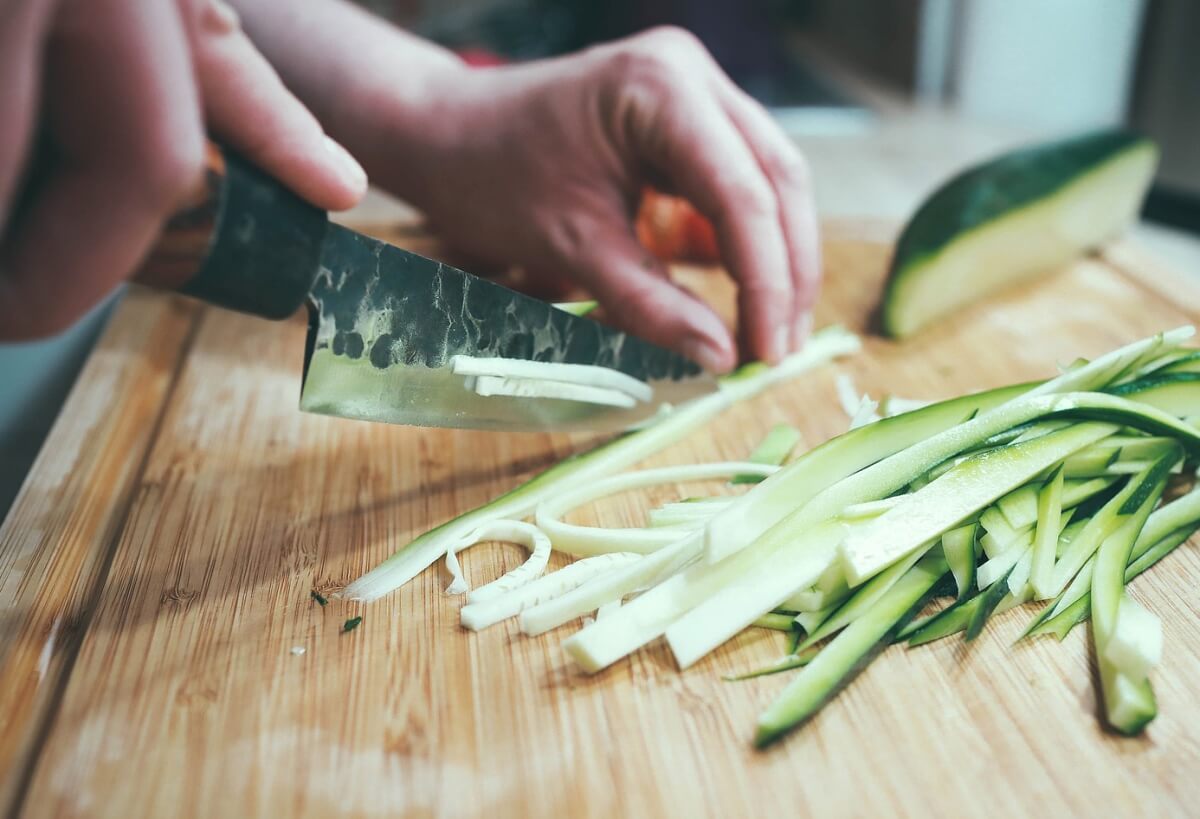 Chop vegetables. Приготовление еды. Кабачок нарезанный. Цукини в японской кухне. Кабачок на деревянном фоне.