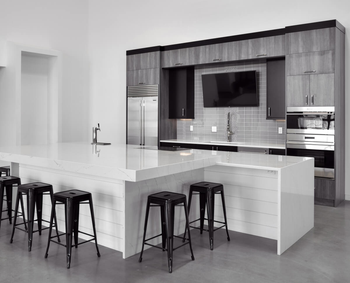 A modern black and white kitchen design with a bright white shiplapped kitchen island with lots of seating.