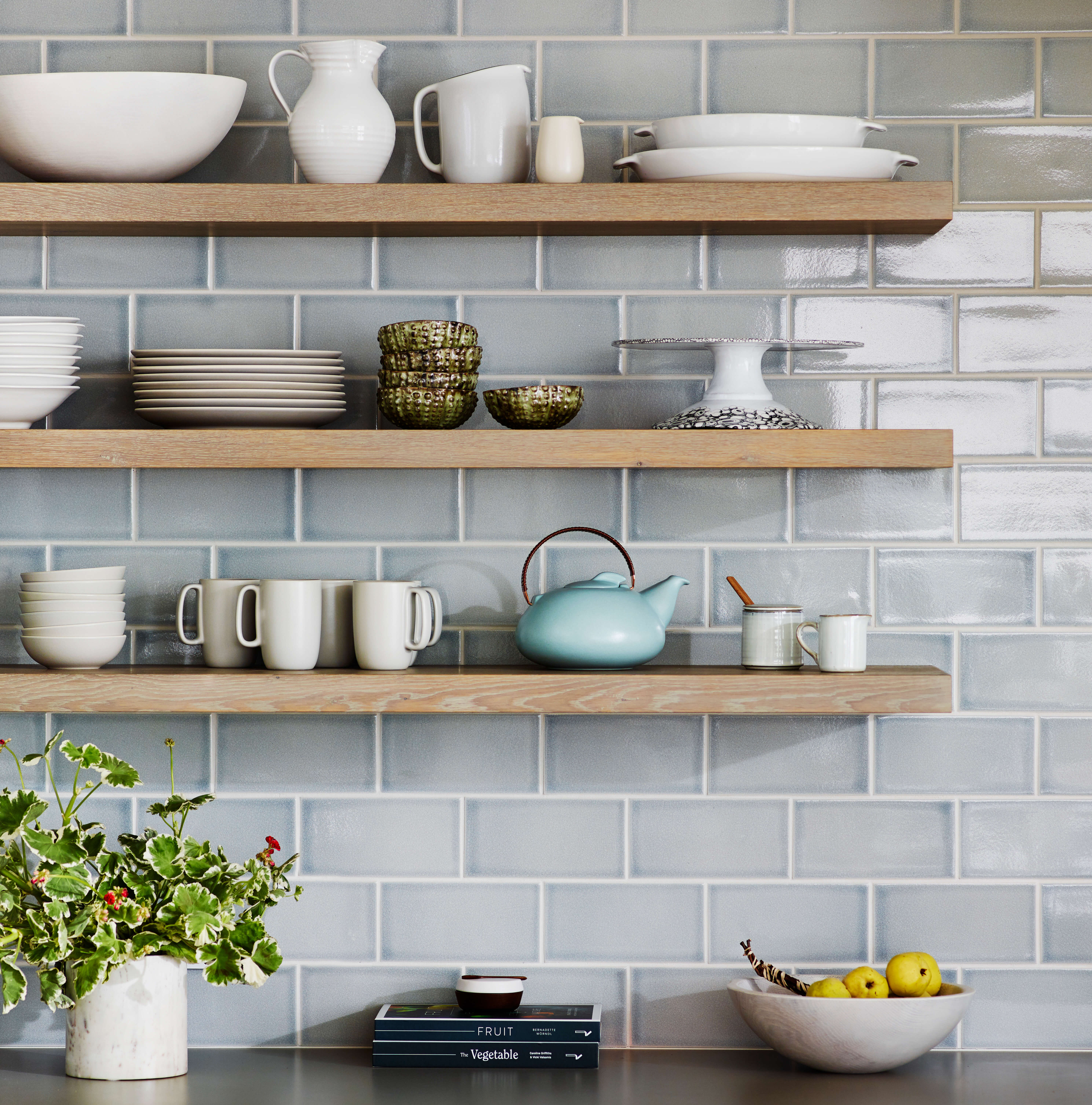 A Scandinavian style kitchen design with light oak floating shelves and pastel blue subway tile backsplash.