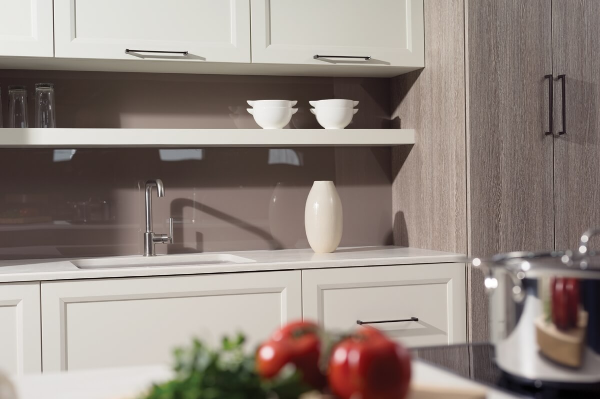 A kitchen sink area with a combination of white painted modern shaker cabinets and slab textured foil cabinets.