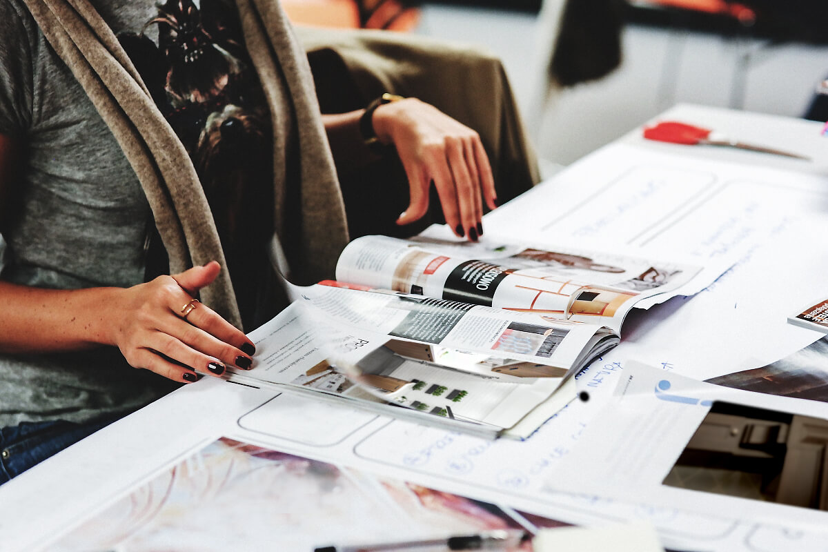 A woman browsing magazines for inspiring photos of kitchens and colors for a home remodel.