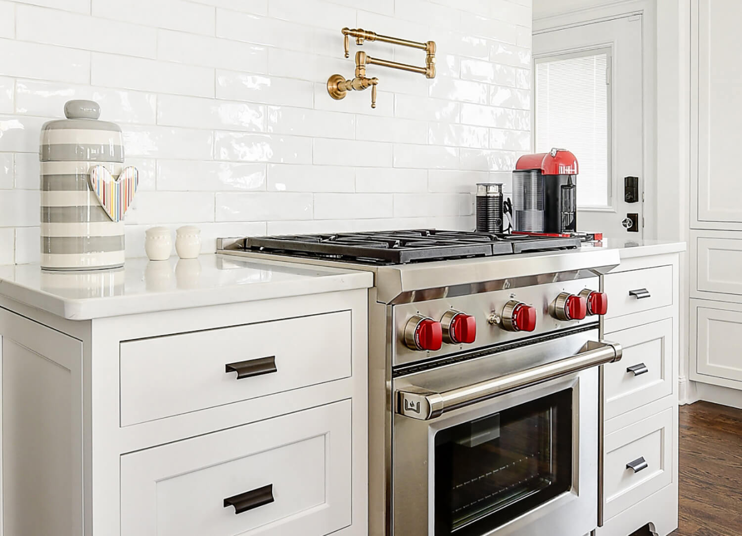 A beautifull all white kitchen with dark hardwood floors, white pianted inset cabinets, and crisp white countertops.