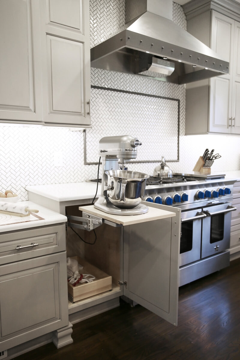 Their well used KitchenAid mixer has a happy home in an appliance lift cabinet next door to the baking center's prep space.