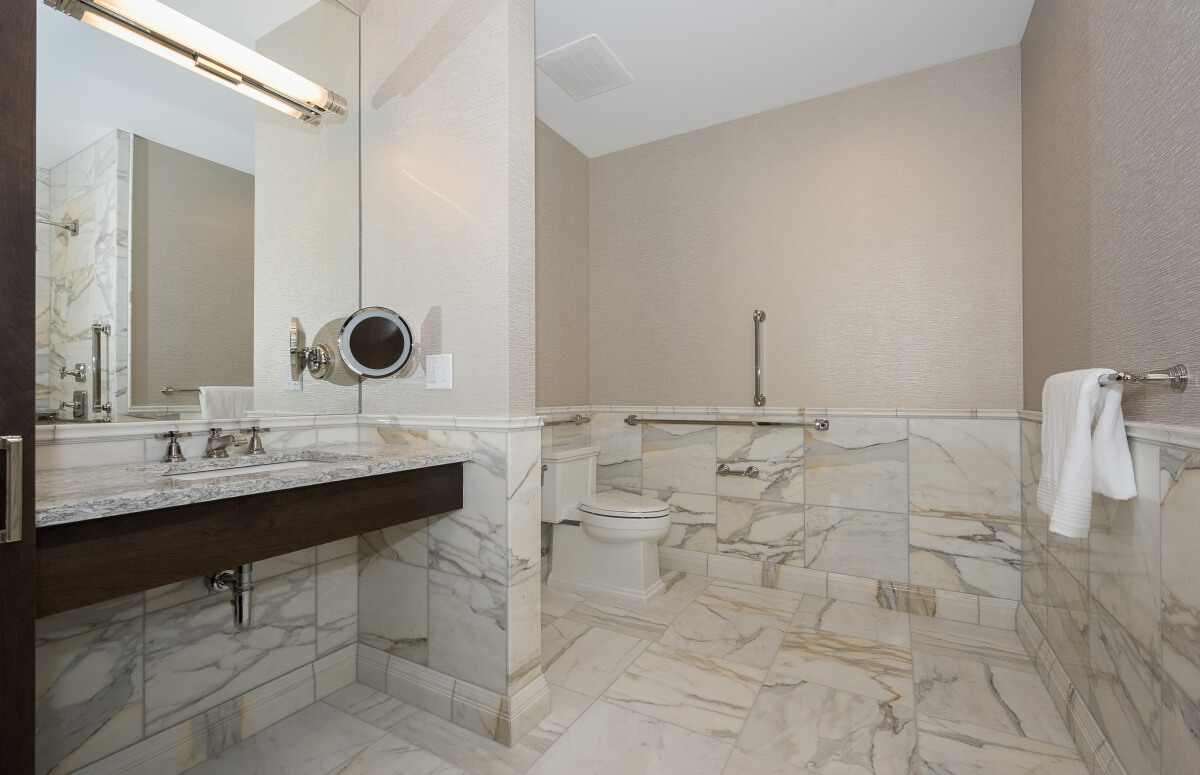 This ADA Compliant bathroom features safety grab bars throughout the space. Designed by Pinnacle Design, Saginaw, Michigan, and photographed by Dan Denardo.