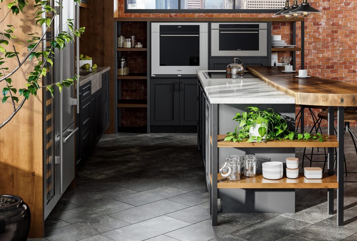 An Industrial style kitchen design in an urban loft with exposed brick walls and ductwork. The modern and rustic cabinets use a black painted finish and accents in a wood with a warm stain. Open shelves and black metal fixtures add to the style. The kitchen island has an open bookcase.