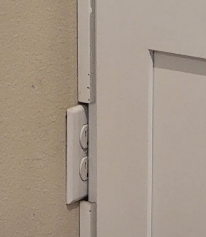 A forgotten outlet half hidden behind a cabinet.