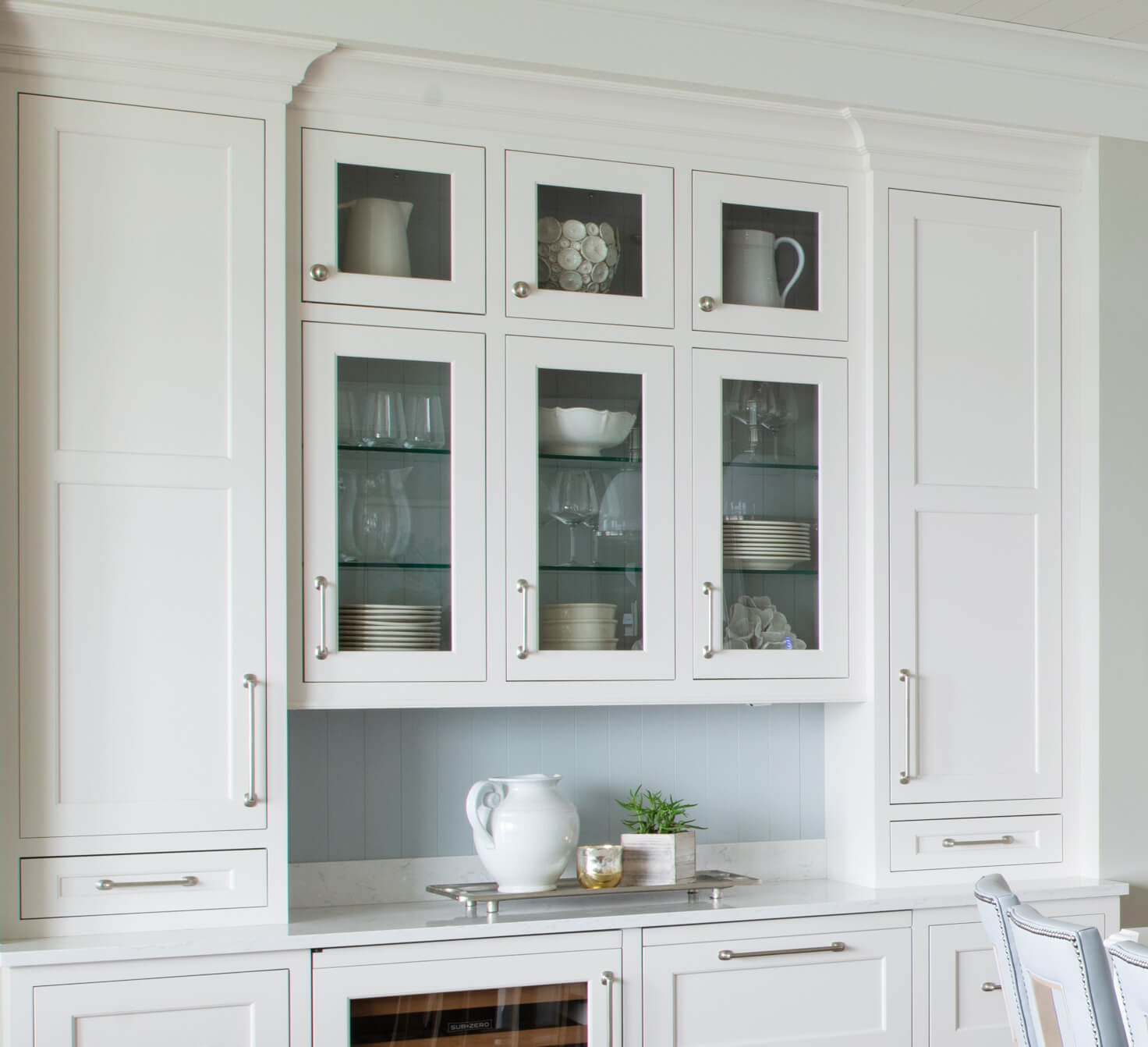 A dining room hutch-like area of the kitchen with glass cabinet doors for displaying and storing serveware and dishware.