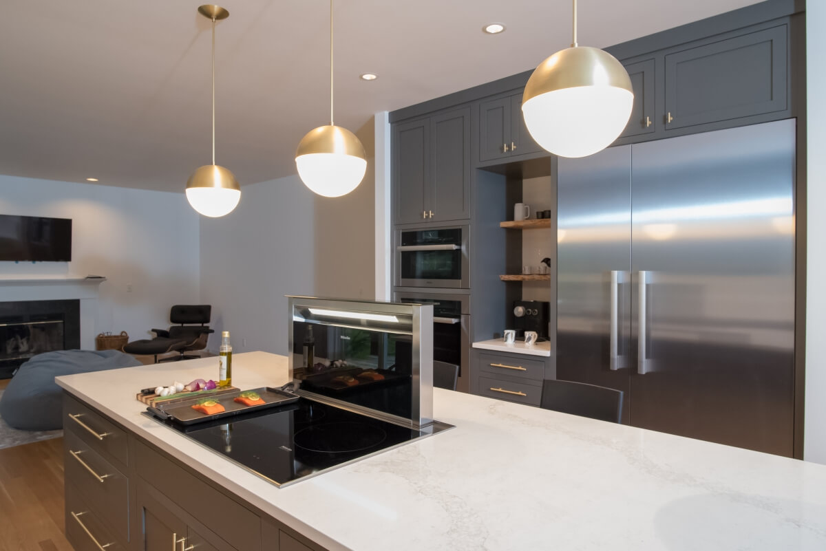 A contemporary kitchen island showing the lift up hidden vent hood for the cooktop in the island.