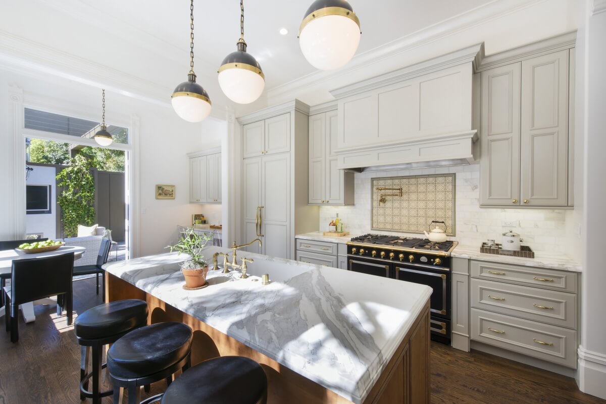 A long lasting classic gray painted kitchen with a gran wood hood and warm stained kitchen island. Dura Supreme kitchen design featuring a 