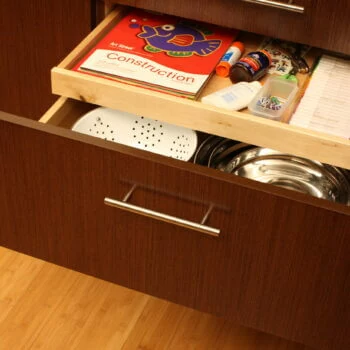 Shallow Roll-Out Above Drawer used for Kids Homework Supplies. Kitchen cabinet storage solutions by Dura Supreme Cabinetry.