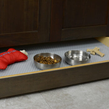 Miscellaneous items can find a home in a Dura Supreme Toe-Kick Drawer hidden at the foot of your cabinets. By adding a Dura Supreme Sink Mat you can create a treat station with toys, bones, and treats for your furry friend. Please note, this is a shallow drawer and can not fit standard depth feeding dishes.