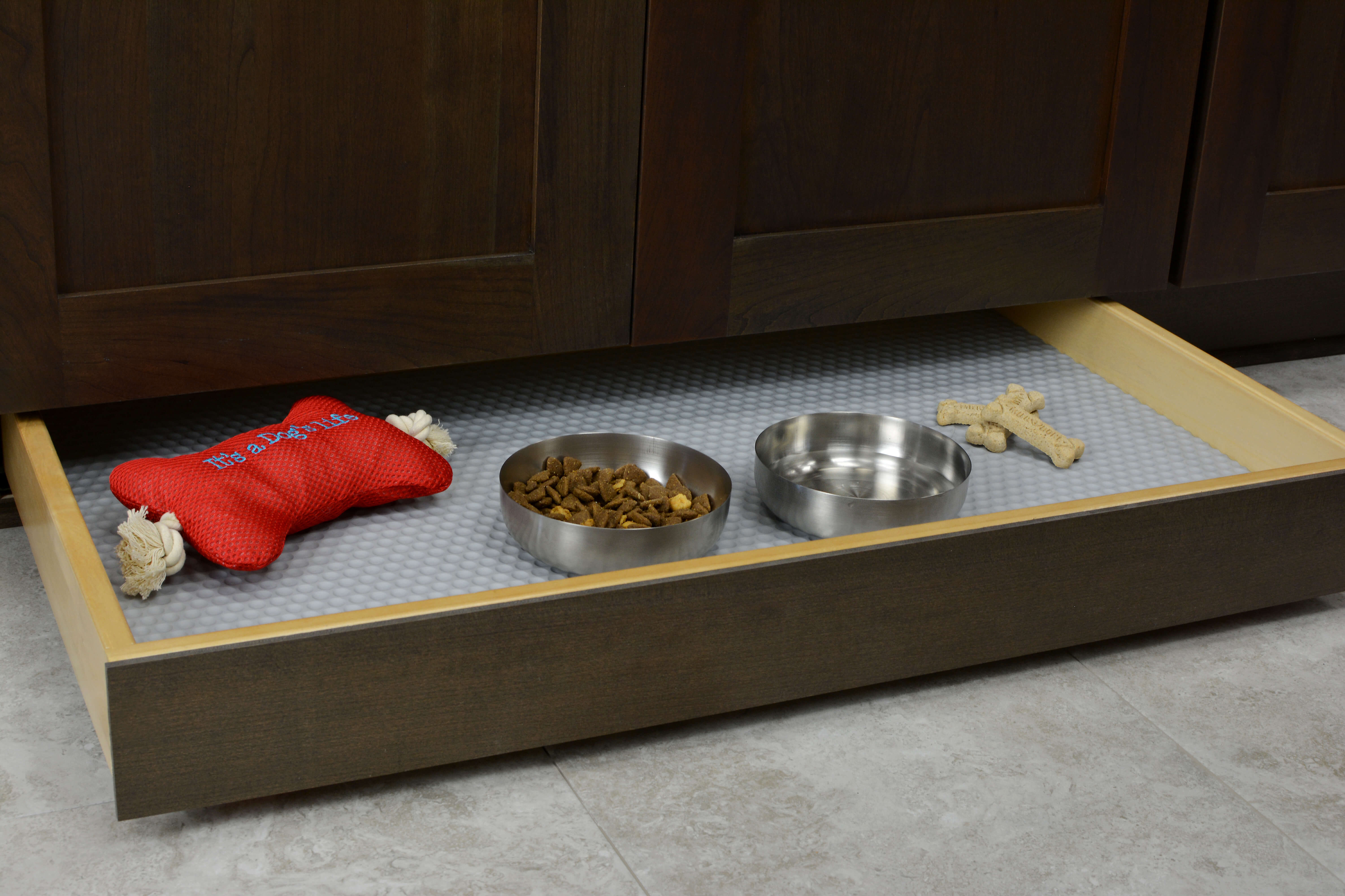 Miscellaneous items can find a home in a Dura Supreme Toe-Kick Drawer hidden at the foot of your cabinets. By adding a Dura Supreme Sink Mat you can create a treat station with toys, bones, and treats for your furry friend. Please note, this is a shallow drawer and can not fit standard depth feeding dishes.