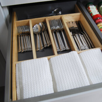 Dura Supreme's wooden cutlery divider tray in a stainless steel drawer creates a beautiful kitchen storage solution for the silverware drawer.