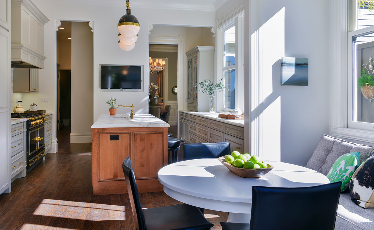 A luxurious kitchen with light gray kitchen cabinets with a warm rusty brown stained kitchen island with a traditional style.