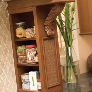 Open shelves hidden to the side of the wood hood tower make a place to store spices, cooking oils, cookbooks, etc. next to the cooktop.