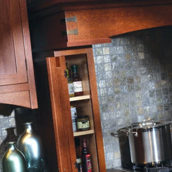 A small storage area next to a wood hood can be turned into practical storage for cooking oils and spices with the hinged cabinet door option.