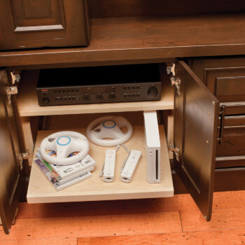 A flat roll-out shelf in a built-in entertainment center cabinet used for easy access to video game equipment, game counsels, DVD/BlueRay players, and other electronic equipment.