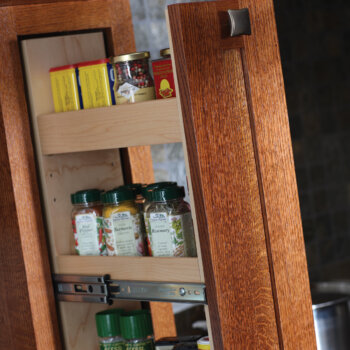 Dura Supreme pull-out spice rack hidden within a wood hood tower or pillar to make easy to access storage for the cook.