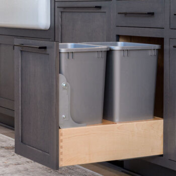 A double trash bin cabinet pull out with a drawer above.