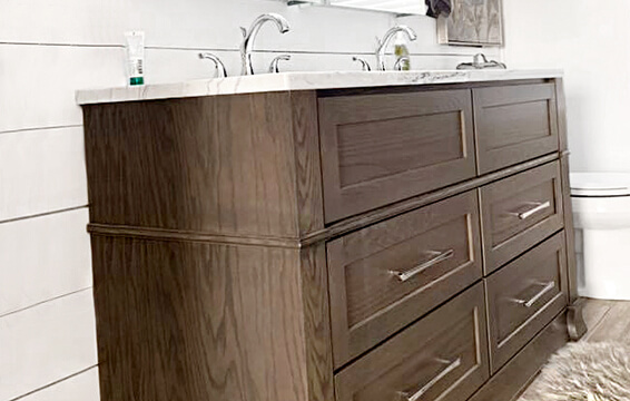 A close up of a gray stained bathroom vanity from Dura Supreme Cabinetry with shiplap walls and modern farmhouse style.