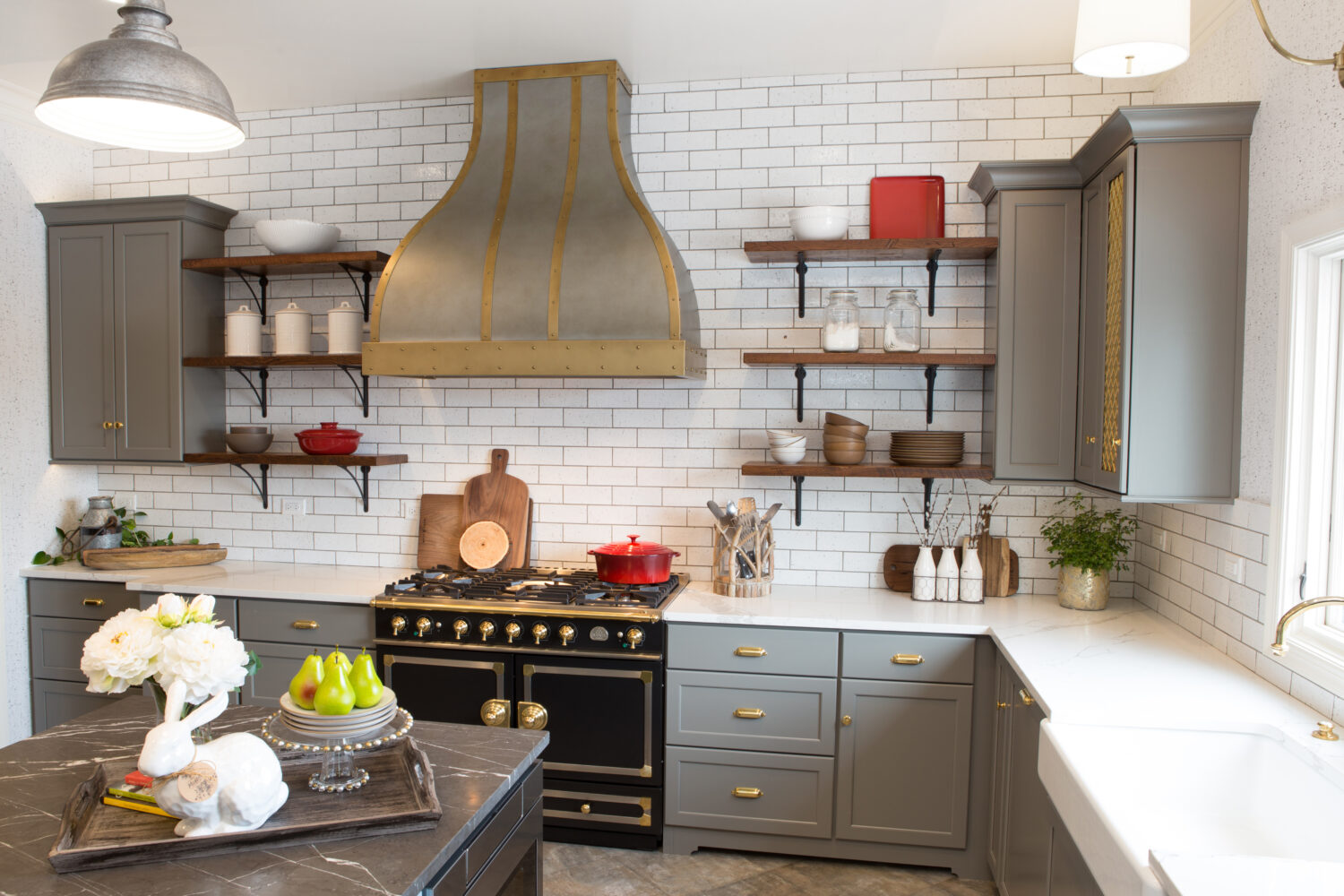 Gray cabinets in a Gray, White, and Gold kitchen design. Beautiful custom Zinc and Brass range hood by Vogler Metalwork & Design proudly centers over the black enamel and brass LaCornue range.