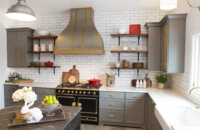 Gray cabinets in a Gray, White, and Gold kitchen design. Beautiful custom Zinc and Brass range hood by Vogler Metalwork & Design proudly centers over the black enamel and brass LaCornue range.