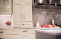 White painted cabinets with a tower sitting on the countertop next to the range and cooktop for extra storage.