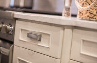 A close of the white painted cabinets with a beautiful, simple molding that emphasizes the flat panel door style.