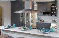 A dark gray painted kitchen deisgn with a peninsula with seating for guests to watch as the chef cooks and entertains.