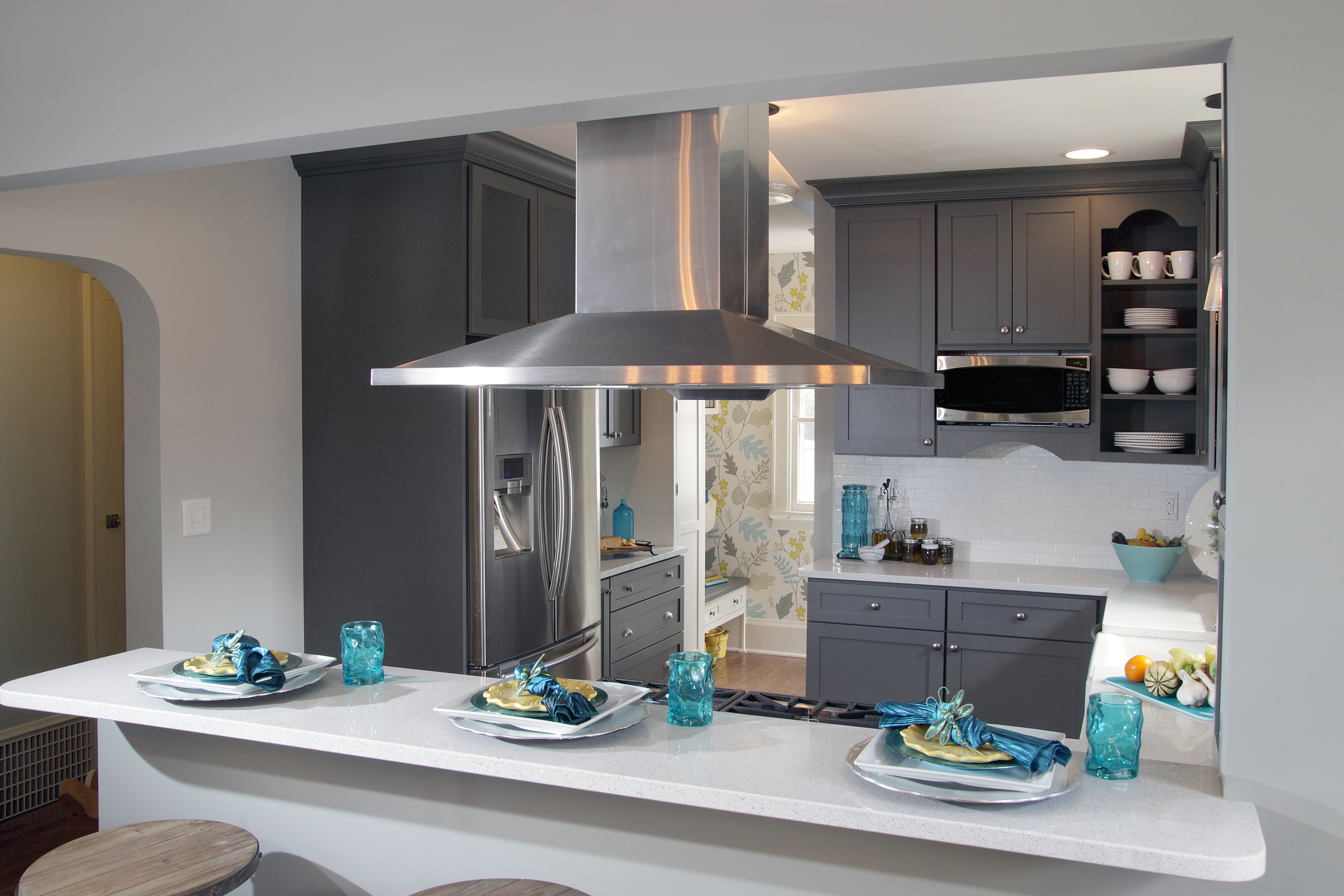 A dark gray painted kitchen deisgn with a peninsula with seating for guests to watch as the chef cooks and entertains.