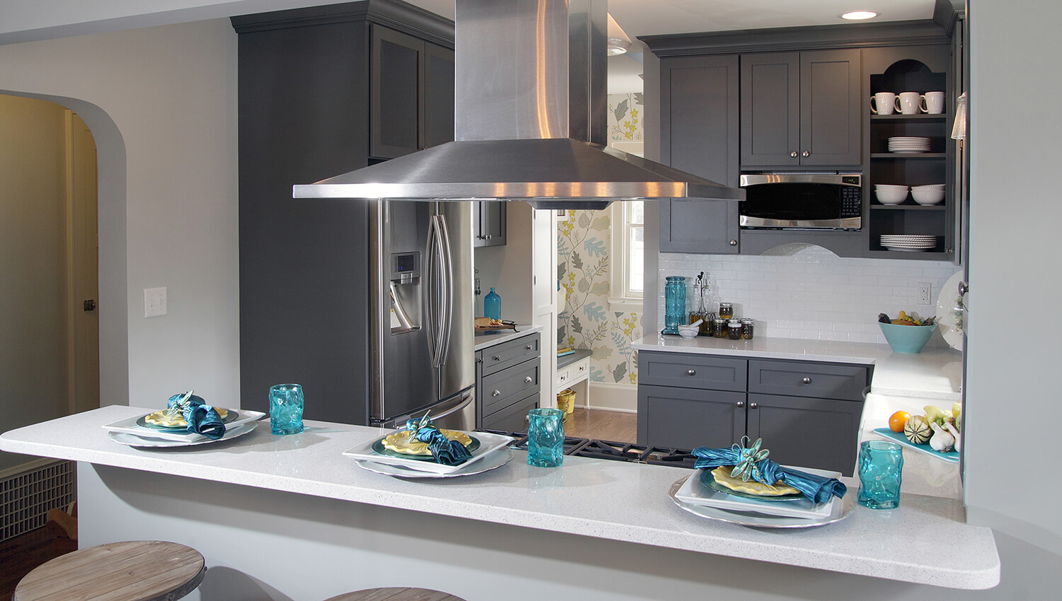 A dark gray painted kitchen deisgn with a peninsula with seating for guests to watch as the chef cooks and entertains.