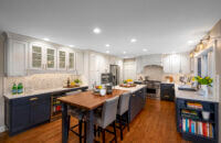 A long kitchen island that is half a workspace with cabinet storage and half casual dining room seating.