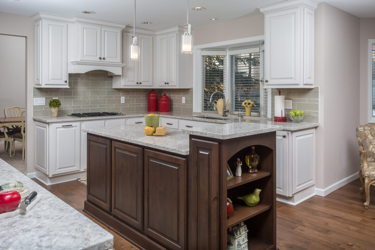 This classic two-tone kitchen remodel uses traditional overlay cabinet doors with raised panel styles. The 2-level kitchen island has a dark stained wood finish while the perimeter cabinets are painted bright white.