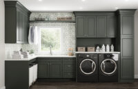 Dark olive green painted cabinets with a custom paint match finish using Dura Supreme's Personal Paint Match program to perfectly match the finish to Sherwin-Williams Rock Bottom paint color. A detailed hand-painted backsplash tile complements the color of the cabinetry throughout the room.