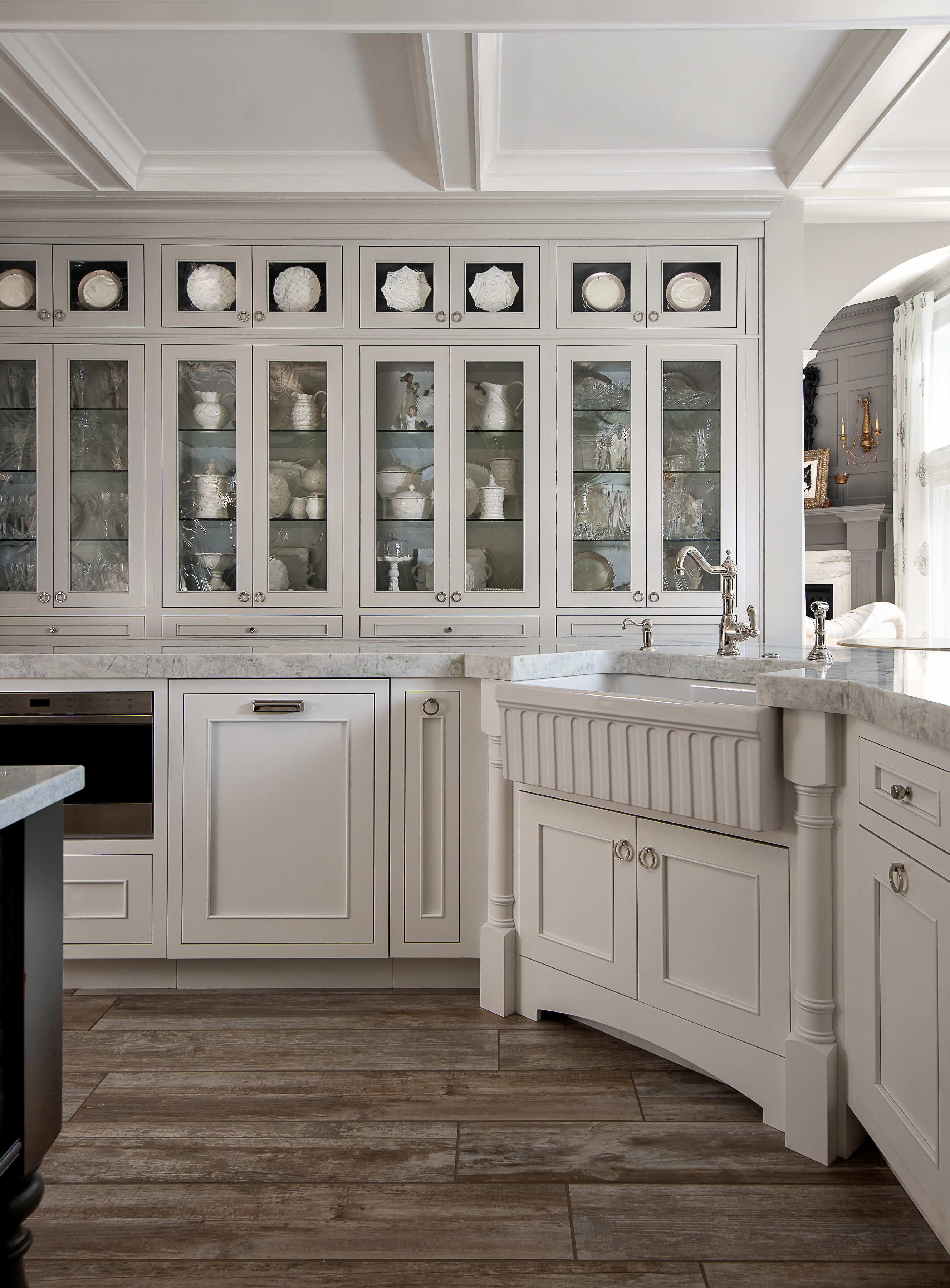 A traditional styled kitchen with white painted cabinets with a row of glass doors for dishware storage and display.