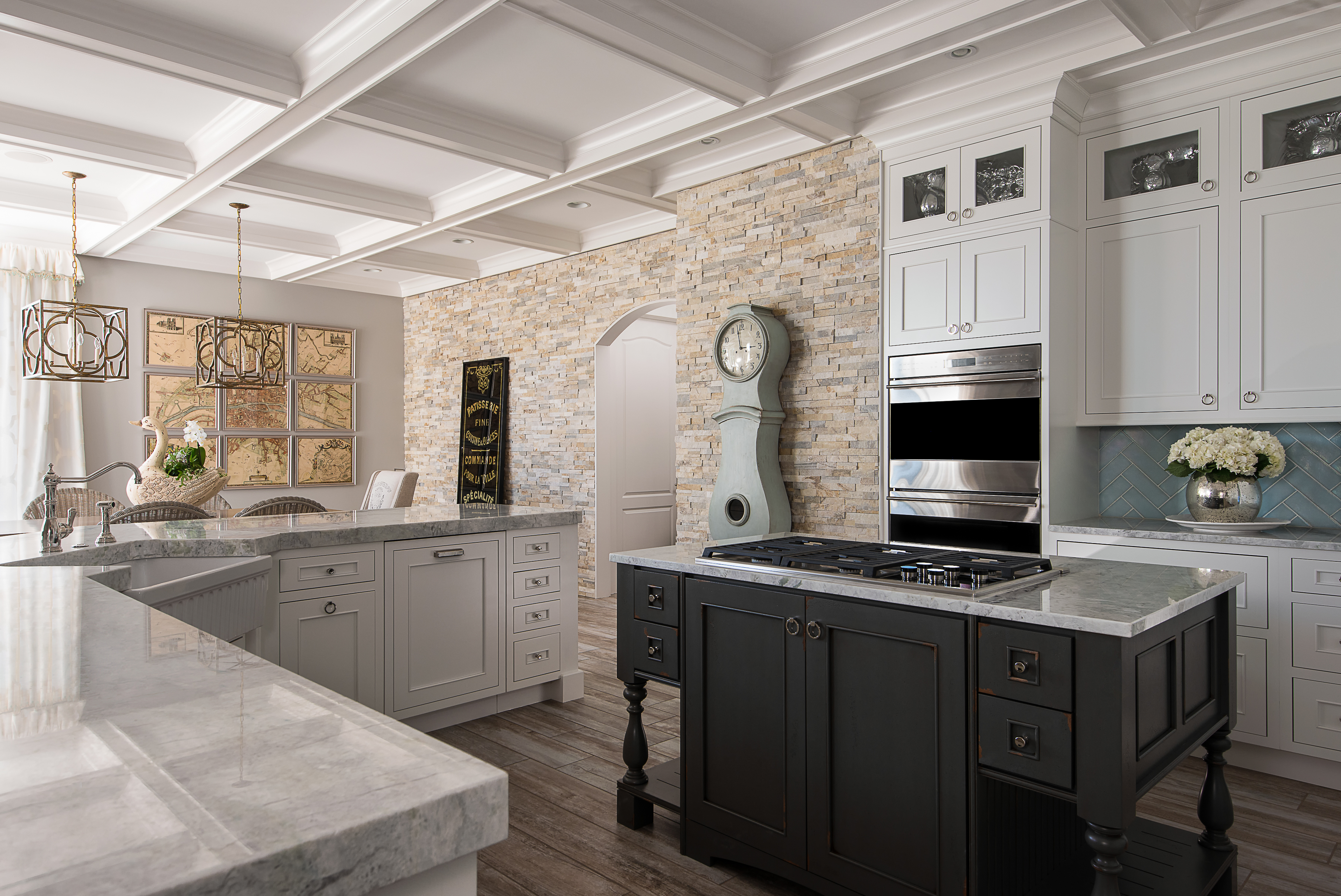 A luxurious kitchen with a black furniture styled kitchen island an L-shaped kitchen island and white painted cabinetry.