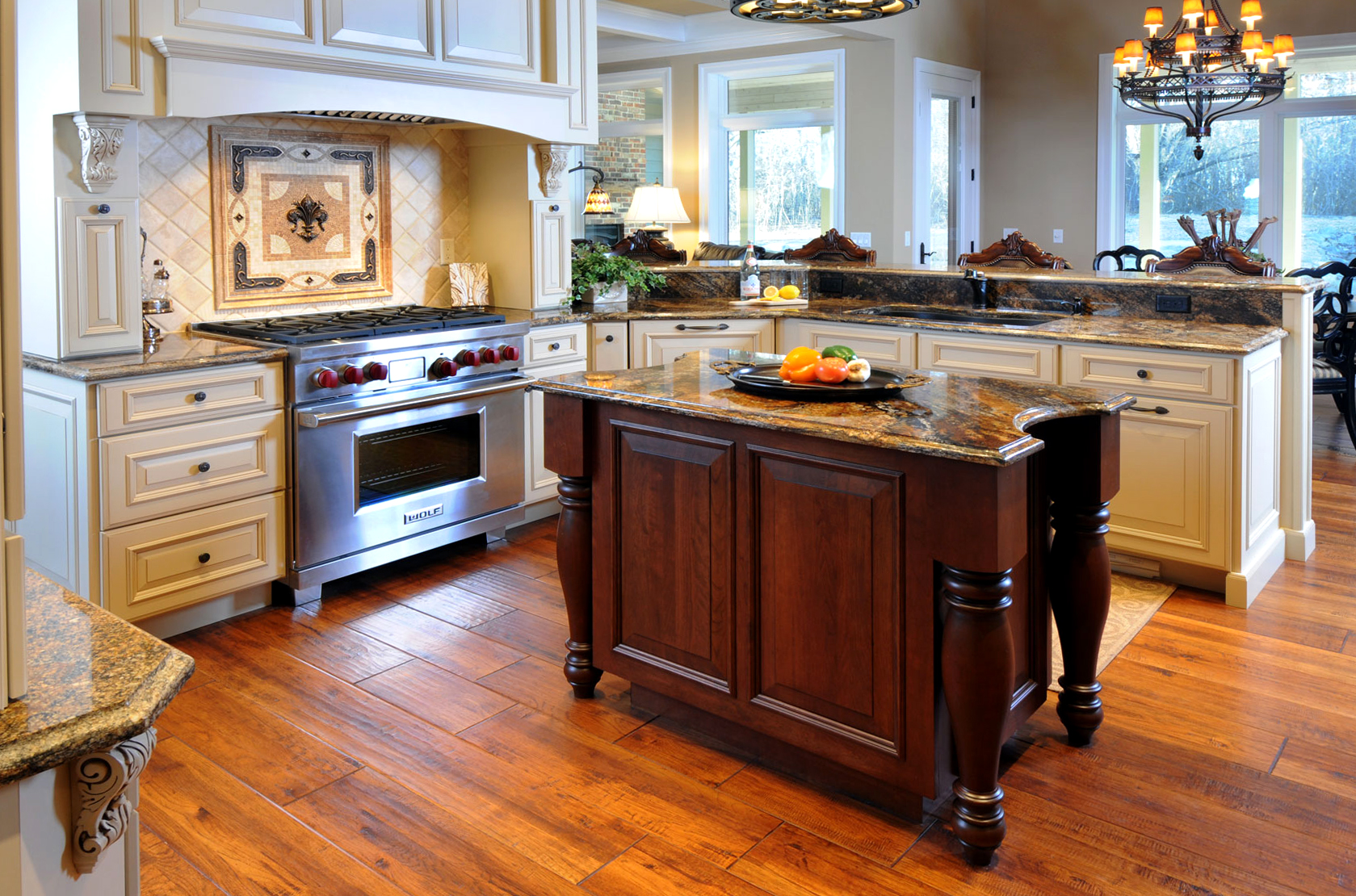 A stunning traditional styled kitchen design with a large wood hood and a table styled kitchen island.