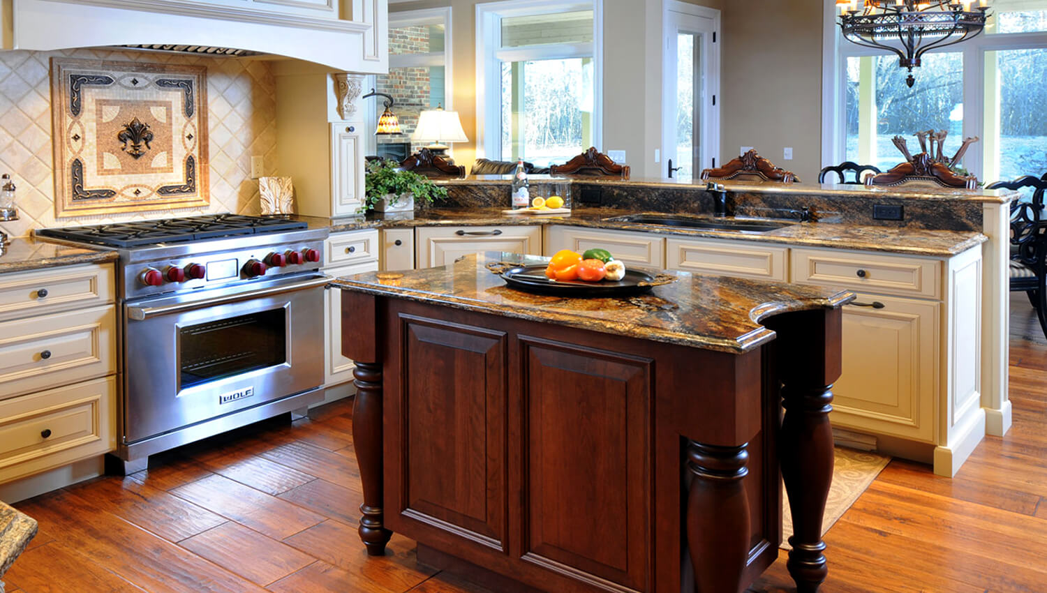 A stunning traditional styled kitchen design with a large wood hood and a table styled kitchen island.